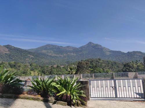 a white gate with mountains in the background at M3 Homes in Munnar