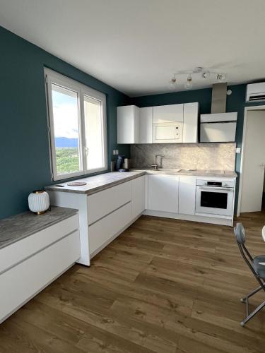 une cuisine avec des placards blancs et une grande fenêtre dans l'établissement Le Miramar La Vue, à Saint Cyprien Plage