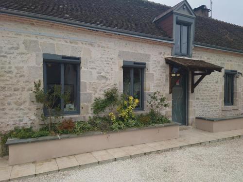 une maison en pierre avec des fleurs dans les fenêtres dans l'établissement Faites comme chez nous !, à Chilleurs-aux-Bois
