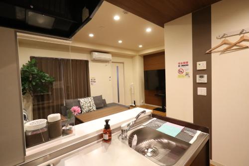 a kitchen with a sink and a living room at ゲストルーム心音-金澤表参道- in Kanazawa