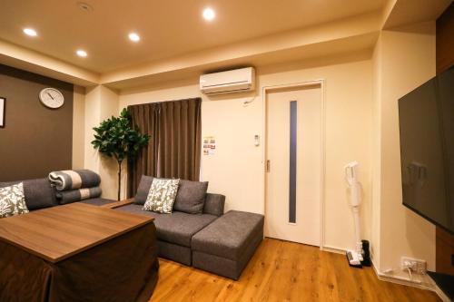 a living room with a couch and a tv at ゲストルーム心音-金澤表参道- in Kanazawa