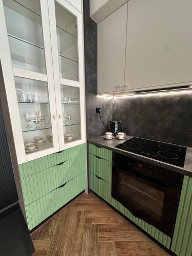 a kitchen with green and white cabinets and a stove at Apartament Z Ogrodem - Paderewskiego 22 in Bartoszyce