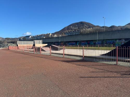 a fence on the side of a road with a bridge at Lovely New 2 Bedroom Condo with Stunning Seaviews in Penmaen-mawr