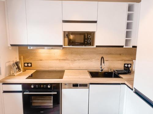 une cuisine avec des armoires blanches, un évier et un micro-ondes dans l'établissement Grand Studio au coeur de Deauville I La Place de Morny et La Gare sont à 5 min à pied, à Deauville