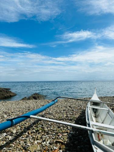 a boat on a rocky beach next to the ocean at Sea View Cabin in Lobo in Batangas City