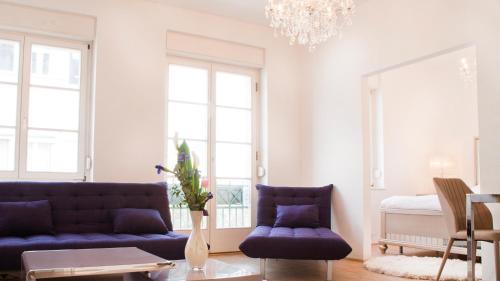 sala de estar con muebles de color púrpura y lámpara de araña en Milford Suites Budapest, en Budapest