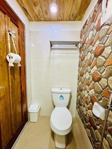 a bathroom with a toilet and a stone wall at Sea View Cabin in Lobo in Batangas City