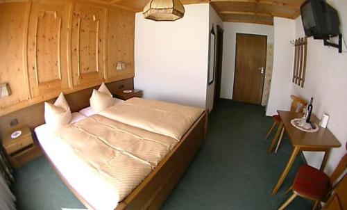 a bedroom with a bed and a desk and a television at Berghaus Maria in Pettneu am Arlberg
