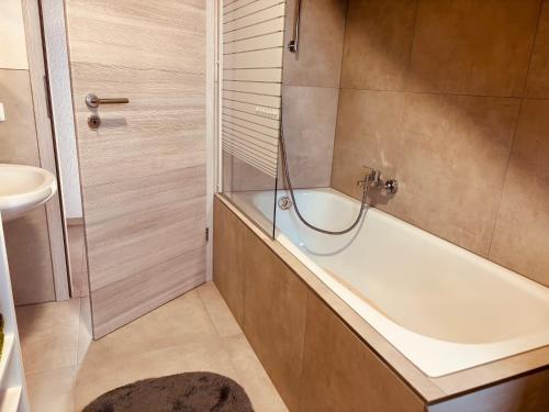 a bathroom with a bath tub and a sink at Ferienwohnung Alpenblick in Pürgen