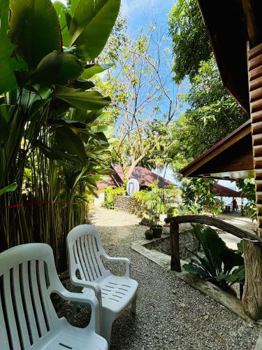 two white benches sitting in a garden with plants at Sea View Cabin in Lobo in Batangas City