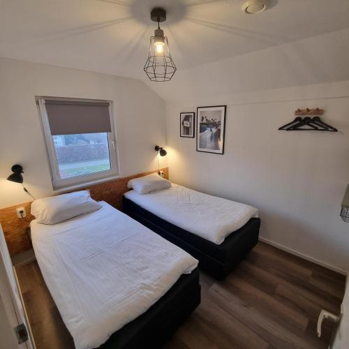 two beds in a room with a window at Jacuzzi & Sauna Villa in Tzummarum