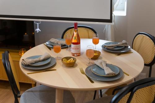 a table with plates and a bottle of wine at Movie Prestige - Elegant - Moderne - Netflix avec VidéoProjecteur - Stationnement facile in Laigneville