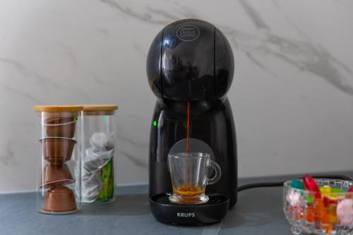 a black coffee maker sitting on a table with a cup at Movie Prestige - Elegant - Moderne - Netflix avec VidéoProjecteur - Stationnement facile in Laigneville
