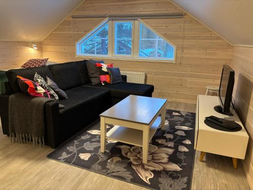 a living room with a black couch and a table at Villa Havu holiday home in Pyhä/Lapland in Pyhätunturi