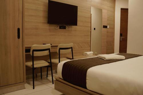a hotel room with a bed and a flat screen tv at Stayon Hotels in Palakkad