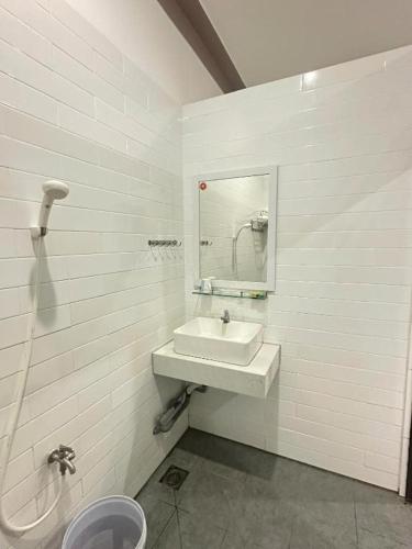 a white bathroom with a sink and a mirror at Nhà Nghỉ Trường An in Ap Rạch Soi