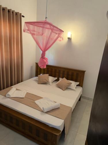 a bedroom with a bed with a pink umbrella on it at Zuulas Palace in Dickwella