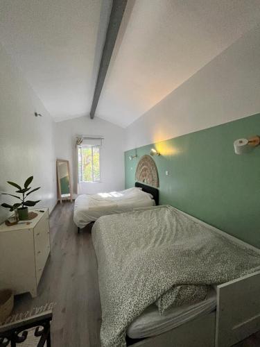 - une chambre avec 2 lits et un mur vert dans l'établissement La bambouseraie de La mitre, à Toulon
