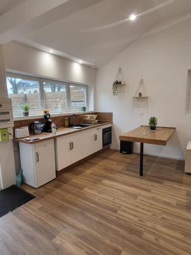 a kitchen with white cabinets and a wooden table at Le Chalet Champenois - Jacuzzi - Terrasse - Calme - Ciné Netflix in Troyes
