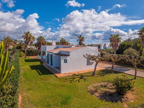 a white house with palm trees and a yard at Kasa K - Slowlife in Binibeca in Binibeca