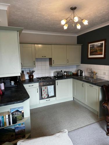 a kitchen with white cabinets and a ceiling at A charming luxury apartment! in Portinscale