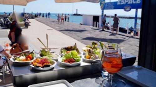 a table with plates of food and a drink on the beach at Appartement avec terrasse in Le Grau-dʼAgde