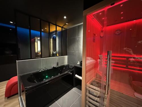 La salle de bains est pourvue d'un lavabo noir et d'un éclairage rouge. dans l'établissement Paradise Sauna Annecy proche du chateau, à Annecy