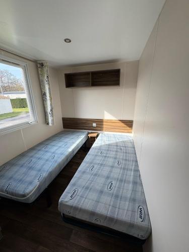 deux lits dans une chambre avec une fenêtre dans l'établissement MOBIL-HOMES LES CHARMETTES 4 Etoîles, aux Mathes