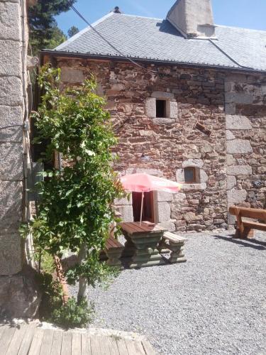a stone building with a bench with a pink umbrella at Hibiscus Gîte in Les Violes