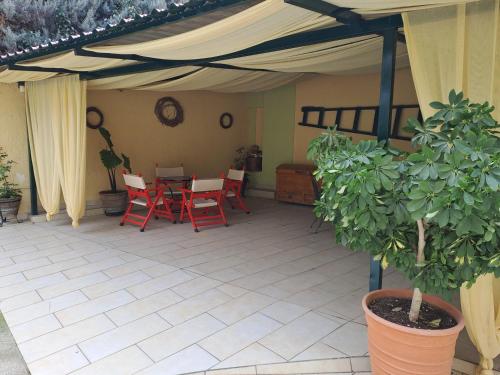 a patio with red chairs and a table under a tent at Vicky's place,near Athens airport in Koropíon