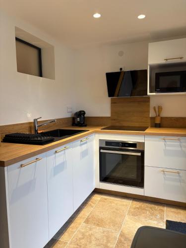 une cuisine avec des armoires blanches, un évier et un micro-ondes dans l'établissement Appartement au bord de mer - Les Issambres, à Roquebrune-sur Argens