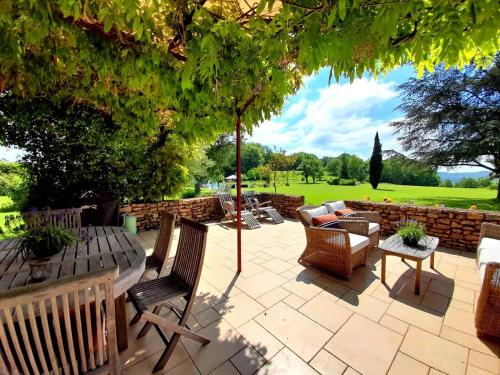 a patio with chairs and a table and an umbrella at Manoir de La Brunie-Grand Longere in Coux-et-Bigaroque
