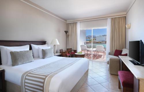a hotel room with a large bed and a balcony at JAZ Dahabeya in Dahab