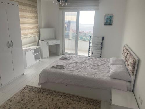 a white bedroom with a bed and a window at TRABZON PANORAMA APART in Trabzon