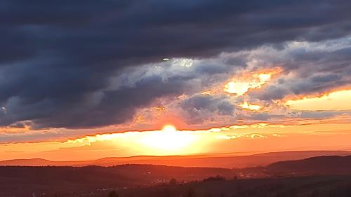 a sunset with the sun poking through the clouds at Agroturystyka Szklana Polana in Huta Szklana