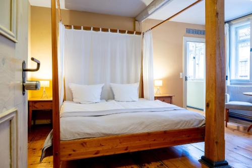 a bedroom with a four poster bed with white sheets at Hotel am Hoken in Quedlinburg
