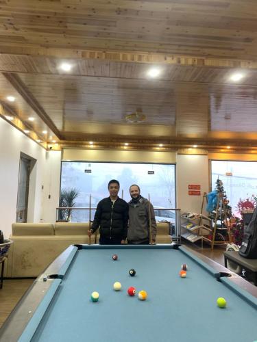 two men standing next to a pool table at Pea Hostel in Sa Pa