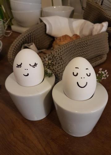 two eggs with faces painted on them sitting in a bowl at Hotel am Hoken in Quedlinburg