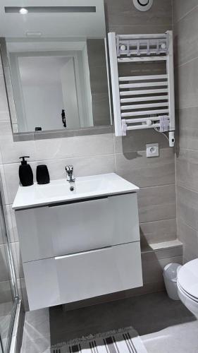 une salle de bain avec un lavabo blanc et un miroir dans l'établissement Le Patcho Charmant studio Confortable & Chaleureux , idéalement situé proche centre ville Quartier Neustadt Tribunal, Contades, à Strasbourg