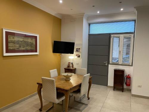 a dining room with a table and chairs and a television at Casa Ferdinando apartment in Naples