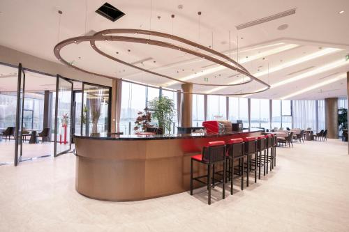 a lobby with a bar with red chairs and windows at Suzhou Qingfeng Mingyue Hotel in Yinshanhunongchang
