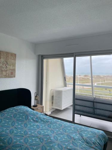 une chambre avec un lit et une grande fenêtre dans l'établissement Port Camargue plage sud, Très bel appartement avec vue mer, au Grau-du-Roi
