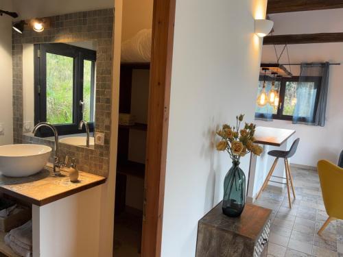 La salle de bains est pourvue d'un lavabo et d'un vase de fleurs sur une table. dans l'établissement Casa Lisandru- Mini-Villa proche des plages, à Viggianello