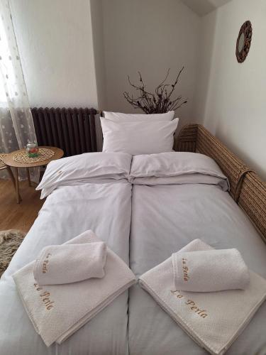 a bed with two white towels on top of it at Apartman La Perla in Vrbas