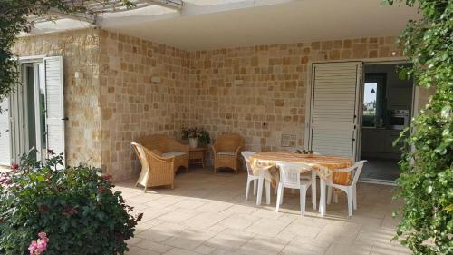 eine Terrasse mit Tisch und Stühlen und einer Backsteinmauer in der Unterkunft Casa Leralora - Elegante villa con piscina, a due passi dal mare in Conversano