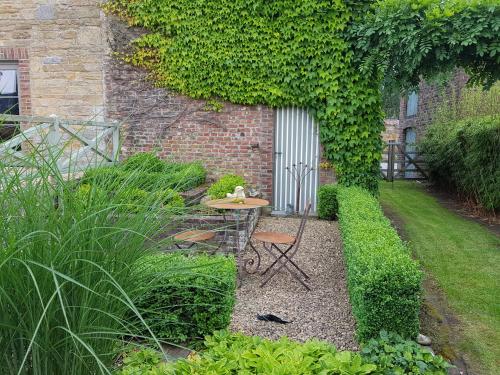 a garden with a table and chairs in front of a building at Gîte Le Charme du Passé in Havelange