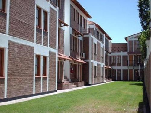 une rangée de bâtiments en briques avec une pelouse verte dans l'établissement Muras Apart Hotel, à Mendoza