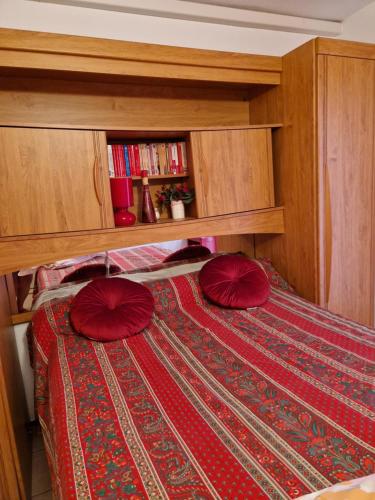 - un lit avec 2 oreillers rouges dans l'établissement Villa lumineuse dans pinède calme et reposante location du dimanche au dimanche, au Cap d'Agde