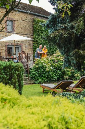 two people sitting at a table in a garden at Gîte Le Charme du Passé in Havelange
