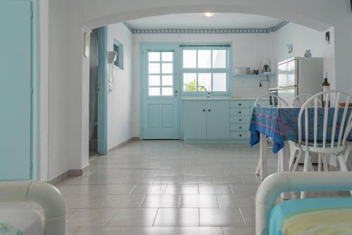 a kitchen with a table and chairs and a refrigerator at Paros Carmel studio-apartment in Logaras